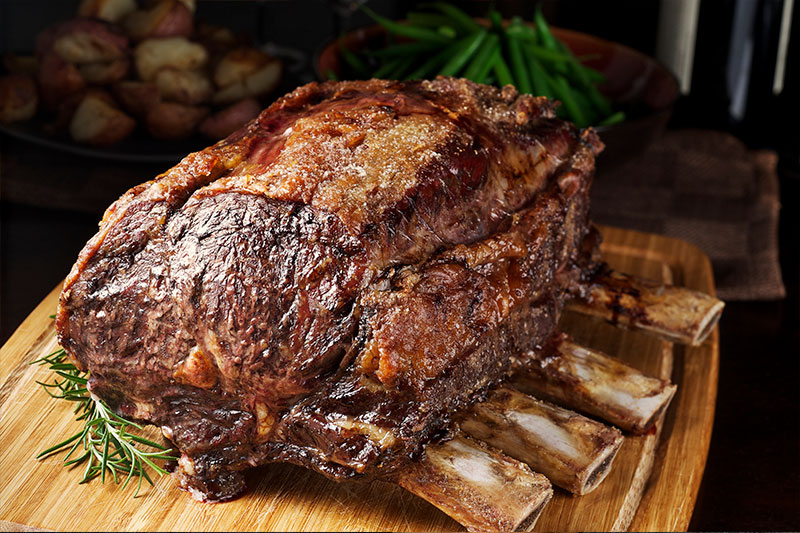 Corte de carne para churrasco costela bovina com osso, assado, posicionado em cima de tábua de madeira. 